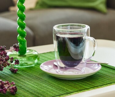 Transparente Tasse mit Holunderbeersaft steht auf einem grünen Tischset zur natürlichen Unterstützung des Immunsystems.